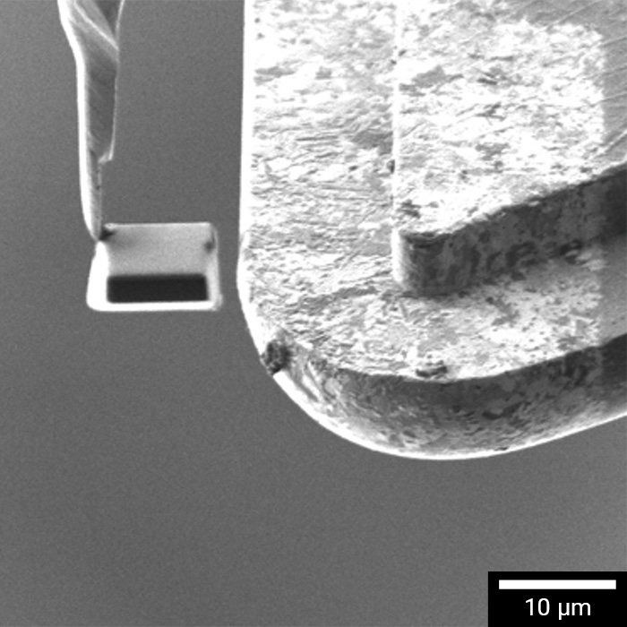 Mit dem Nanomanipulator herausgehobene vorgefertigte Siliziummaske im TESCAN TrueX-Sectioning Workflow.